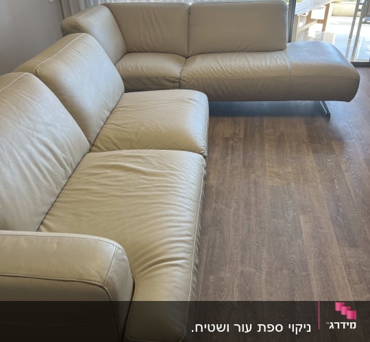 ספות עור בהירות על רצפת עץ בחדר מואר